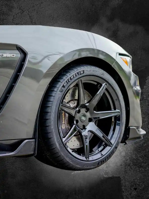 Custom black alloy wheel with five split spokes mounted on a silver vehicle.