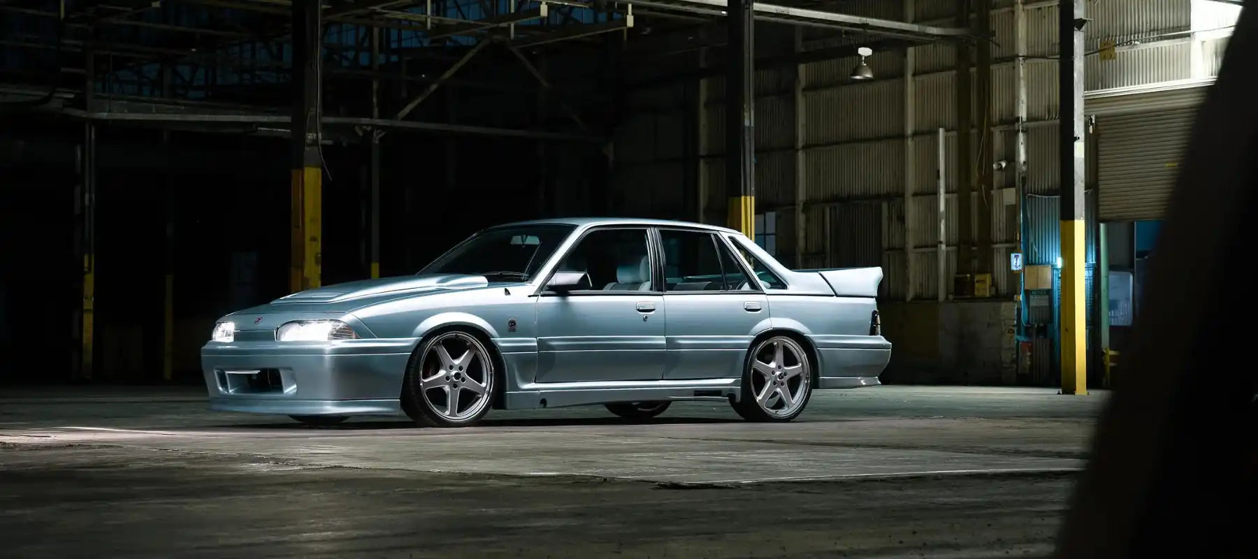 Light blue modified Holden Commodore VL with aftermarket wheels and body kit.