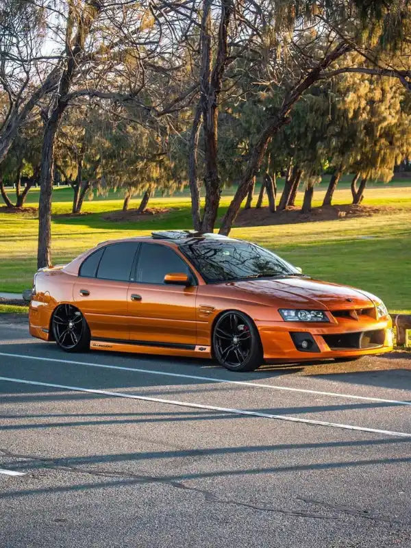 Modified orange Holden Commodore sedan with black wheels and lowered suspension.