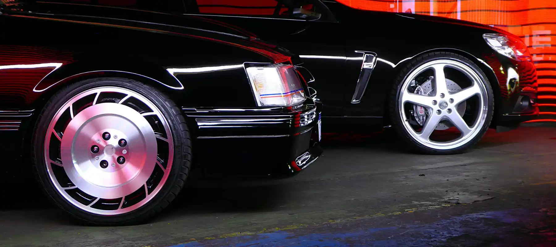 Two contrasting car wheels - one with a retro-styled pink disc design and one with a modern silver five-spoke design.