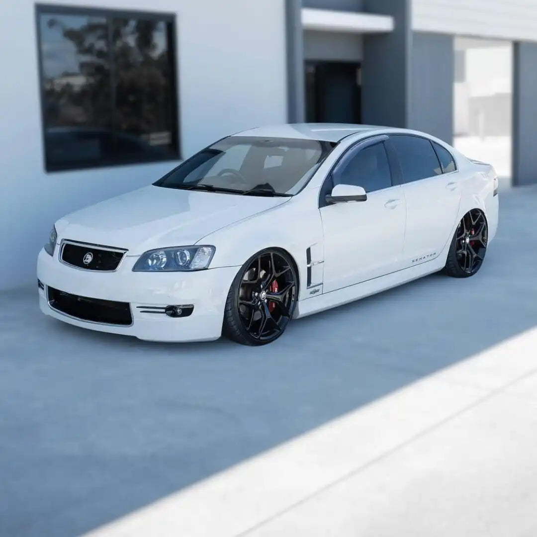 White modified Holden Commodore sedan with black wheels and lowered suspension.